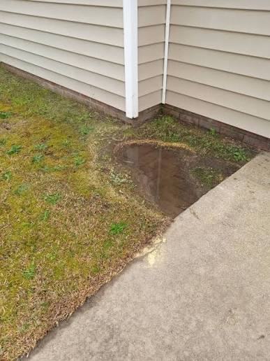 Standing water pooled at home corner where downspout should be