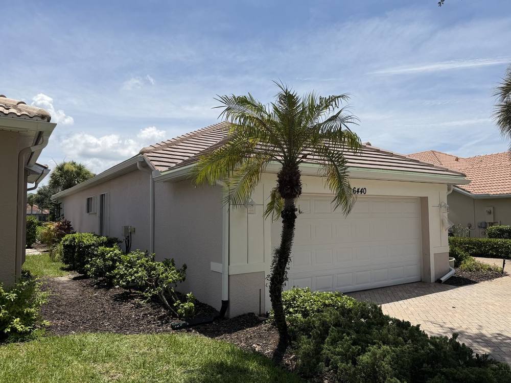 Clean white seamless gutter run on cream home with tile roof
